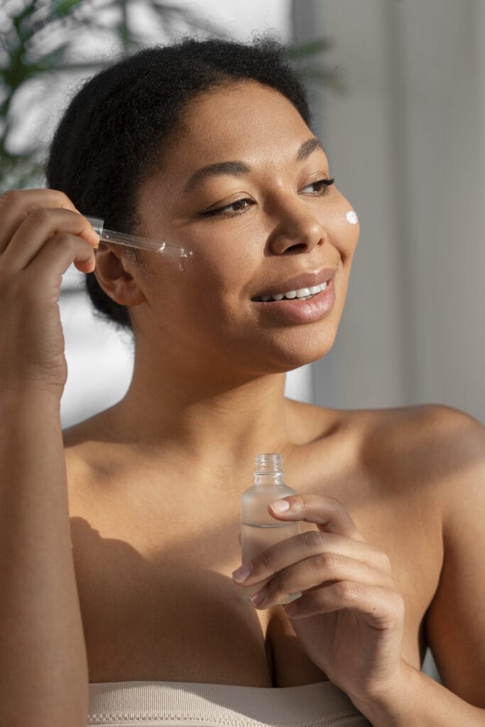 woman smiling applying facial skin care serum product on her face with a dropper