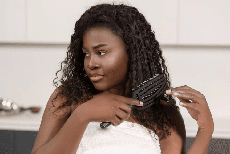 woman combing her hair or wig with a tangle teaser on wash day routine