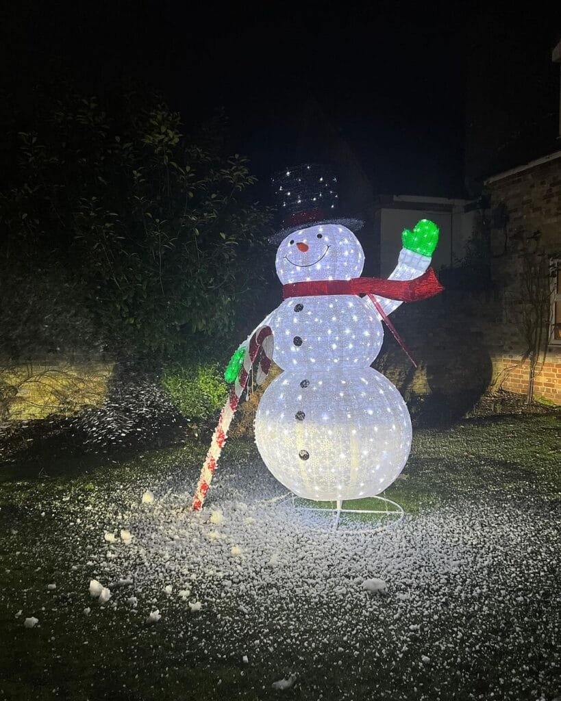 snowman wearing a hat and a scarf waving outside decoration